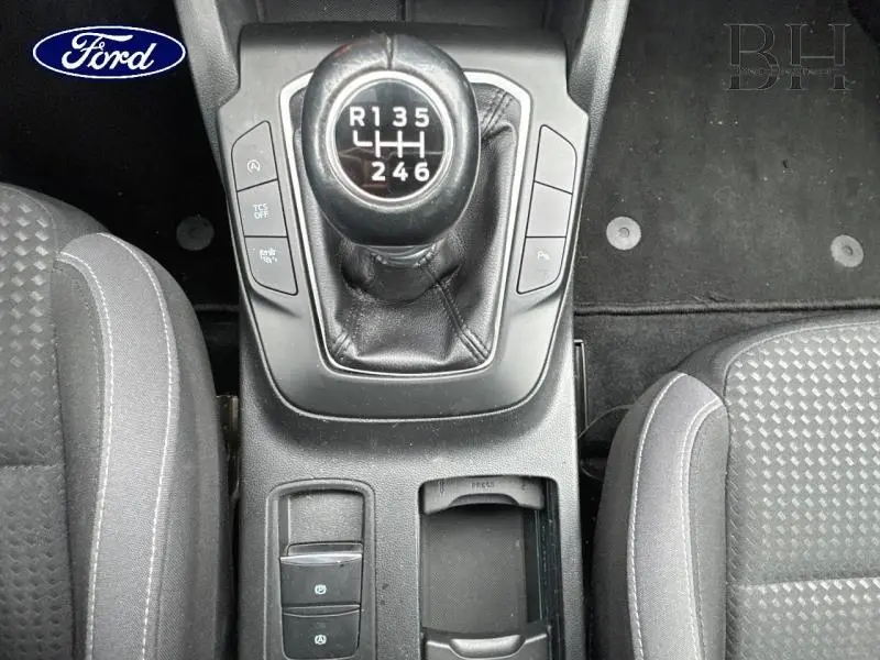 Vue plongeante sur le levier de vitesses manuel et la console centrale du Ford Focus SW blanc, avec sièges tissu gris.