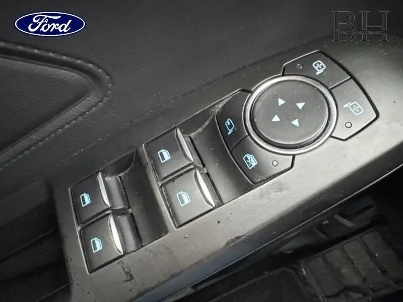 Gros plan sur les commandes de lève-vitres et réglages des rétroviseurs côté conducteur d’une Ford Focus SW 2020.