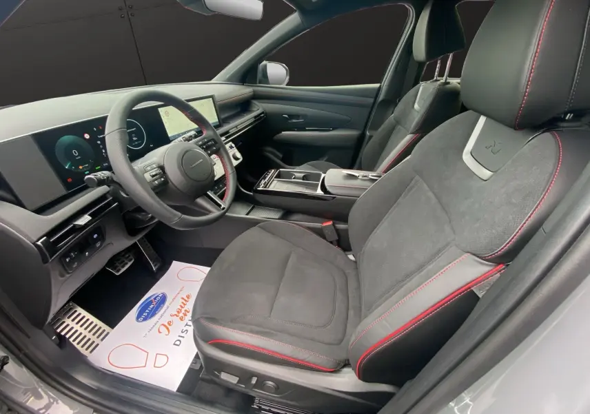 Vue intérieure côté conducteur du Hyundai Tucson 2026 gris Shadow, sièges cuir/Alcantara noirs avec surpiqûres rouges N Line.