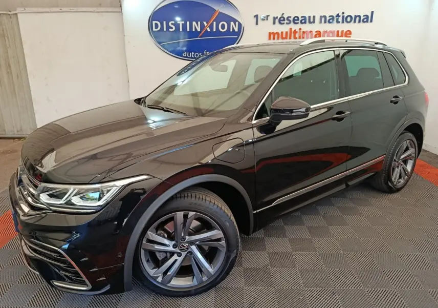 Vue 3/4 avant droit du Volkswagen Tiguan 1.4 eHybrid noir avec jantes alliage et détails R-Line en showroom.