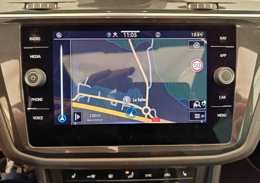 Écran tactile central du Volkswagen Tiguan 2023 affichant la navigation, entouré de commandes noires brillantes.