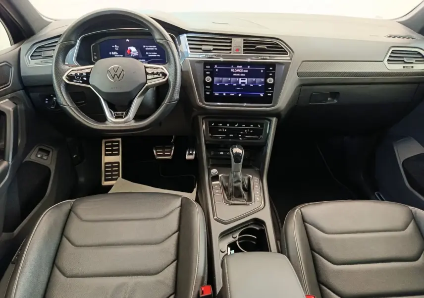 Vue intérieure avant du Volkswagen Tiguan 1.4 eHybrid 2023 avec tableau de bord numérique et sièges cuir noirs.