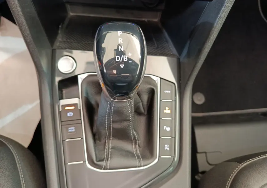 Vue rapprochée du levier de vitesse automatique noir avec coutures blanches du Volkswagen Tiguan hybride rechargeable.