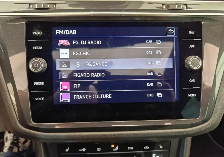 Écran tactile central du Volkswagen Tiguan noir 2023 affichant les stations radio FM/DAB en intérieur.
