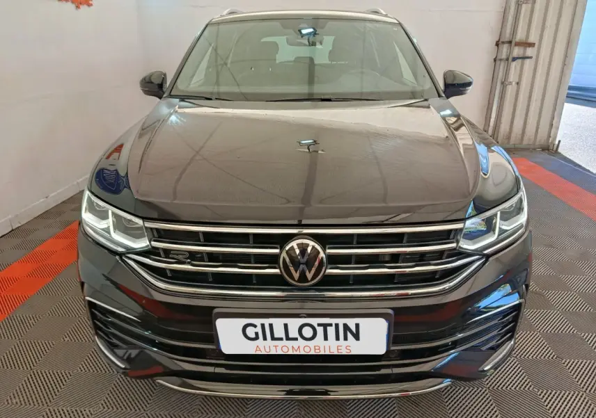 Vue avant du Volkswagen Tiguan noir 1.4 eHybrid R-Line Exclusive avec calandre chromée et phares LED allumés.