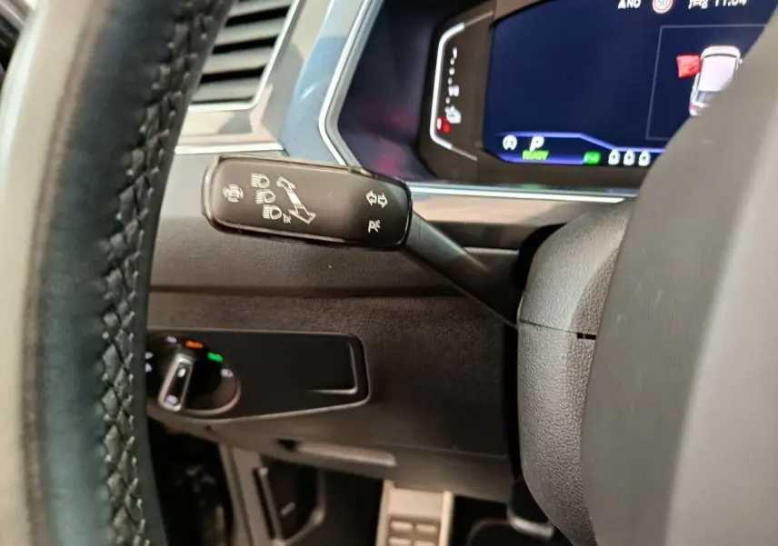 Vue rapprochée du commodo de clignotant et tableau de bord numérique du Volkswagen Tiguan noir 2023 hybride rechargeable.