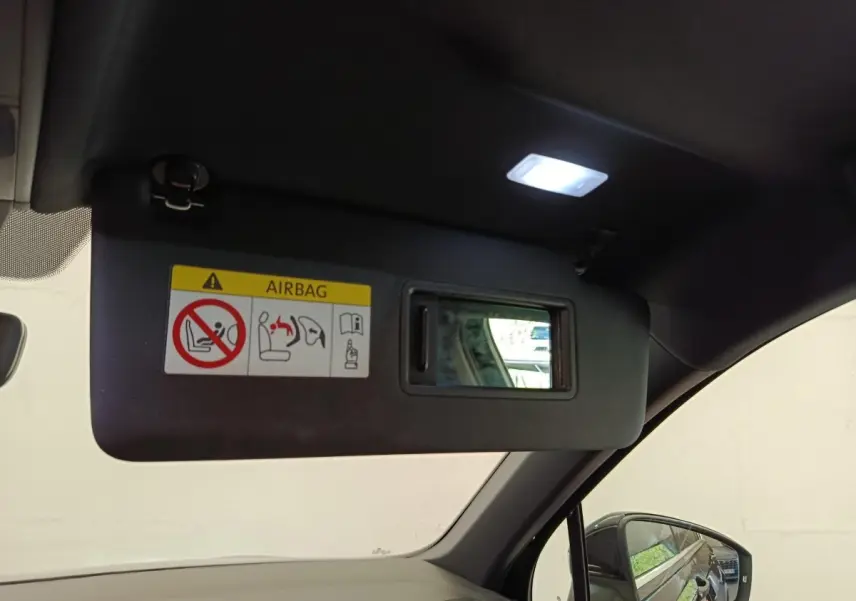 Vue intérieure du pare-soleil côté conducteur du Volkswagen Tiguan noir 2023 avec miroir et avertissement airbag.