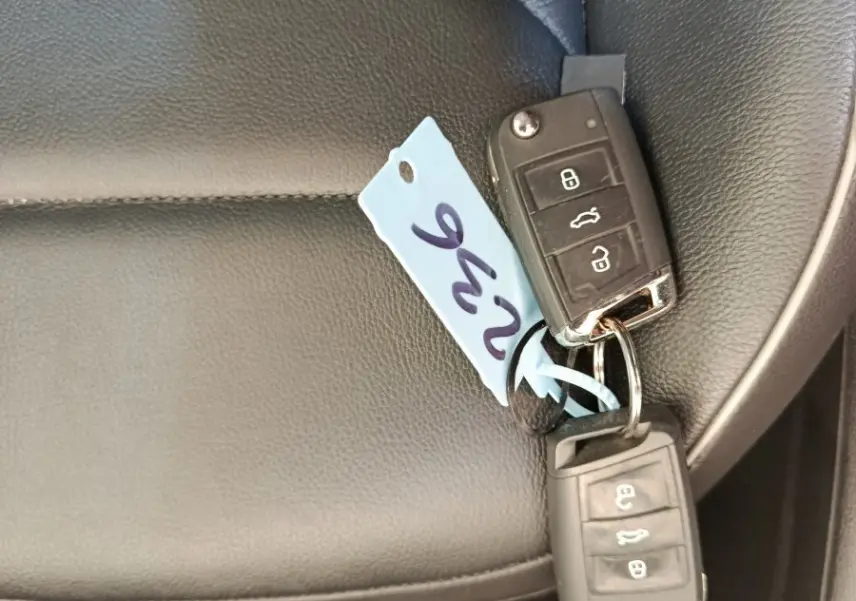 Clé de voiture Volkswagen posée sur un siège en cuir noir à l'intérieur du véhicule, vue rapprochée.