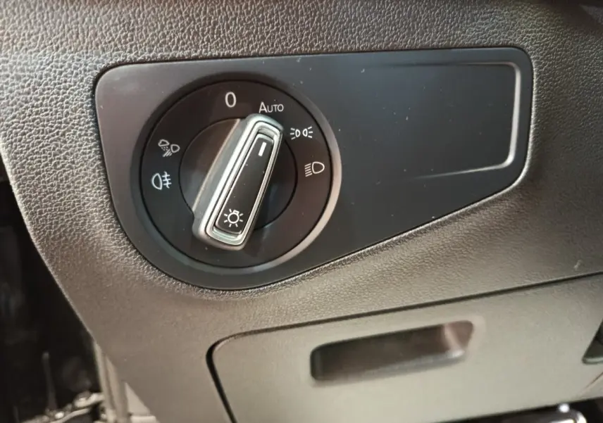 Gros plan sur la molette de réglage des phares dans l’habitacle noir du Volkswagen Tiguan 1.4 eHybrid 2023.