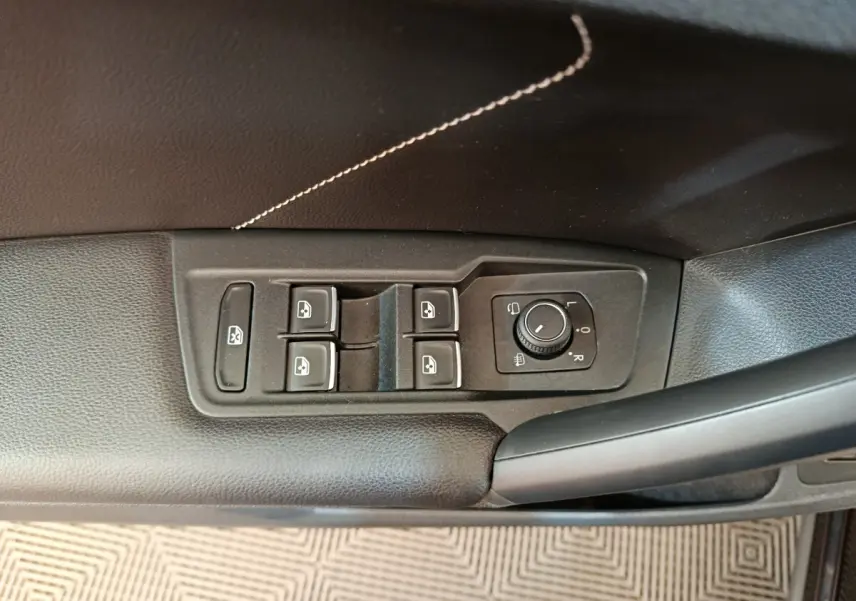 Vue rapprochée des commandes de lève-vitres et réglage des rétroviseurs côté conducteur du Volkswagen Tiguan noir 2023.