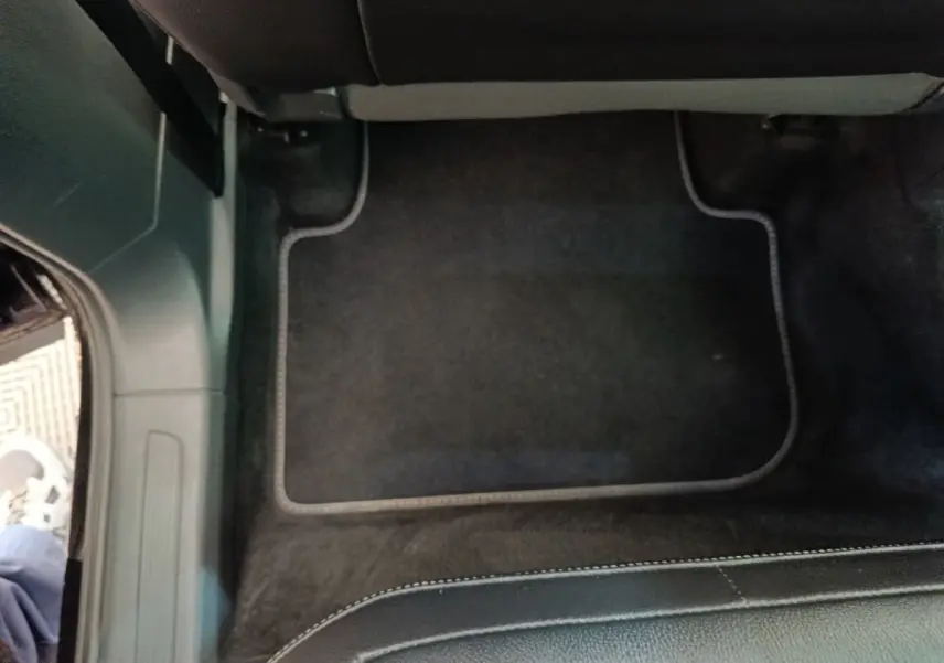 Vue du sol côté passager avant du Volkswagen Tiguan noir 2023, avec tapis de sol et partie inférieure du siège visible.