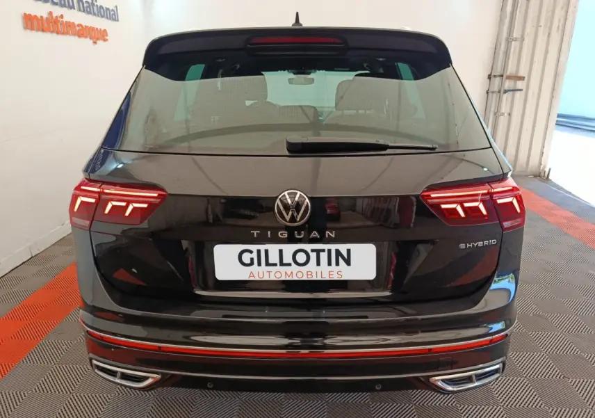 Vue arrière d'un Volkswagen Tiguan noir hybride rechargeable avec feux LED et double sortie d'échappement chromée.