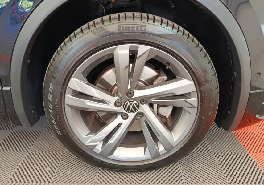 Gros plan sur la roue avant droite du Volkswagen Tiguan noir, mettant en valeur la jante alliage et le pneu Pirelli.