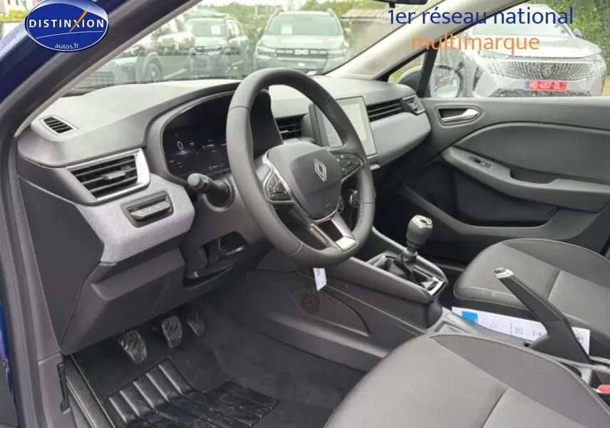 Intérieur de Renault Clio V bleu iron, vue côté conducteur, volant multifonction et boîte manuelle visibles.