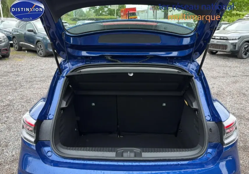 Coffre ouvert vu de l'arrière d'une Renault Clio V bleu iron, avec feux arrière LED visibles.