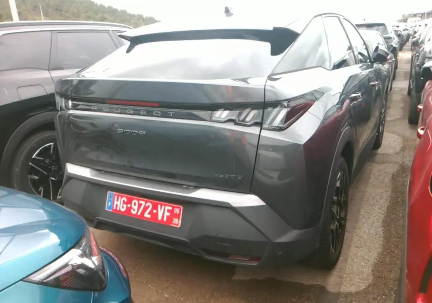 Vue 3/4 arrière d'un Peugeot 3008 2025 gris foncé avec jantes alliage 19'' noir brillant sur un parking.
