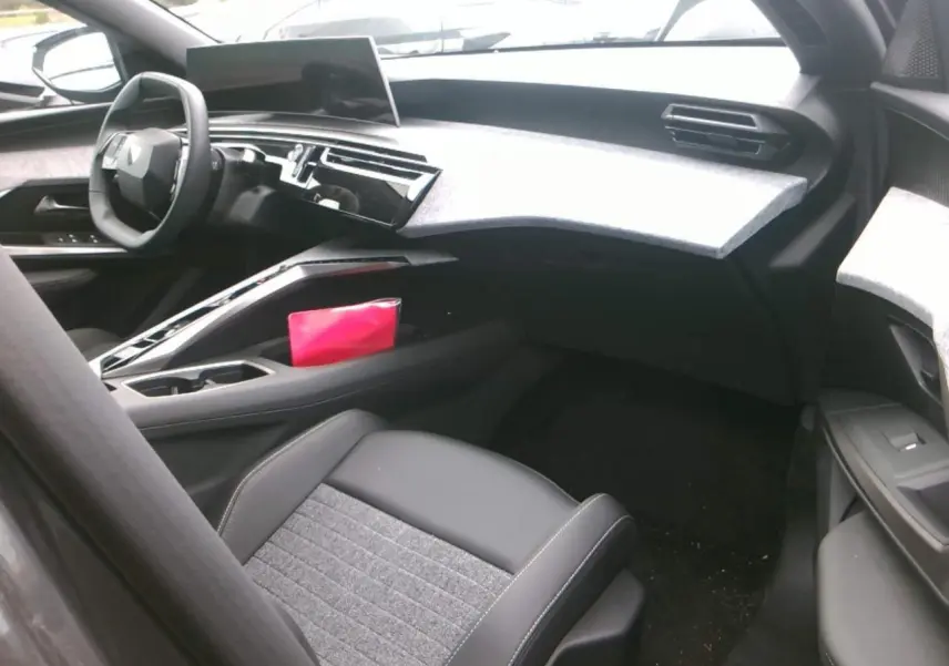 Intérieur du Peugeot 3008 2025 vu côté passager, tableau de bord gris clair et siège tissu noir et gris.