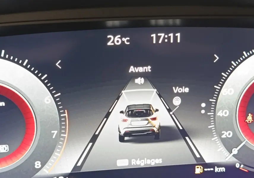 Affichage numérique du tableau de bord montrant une voiture blanche vue de dos avec alertes de voie et température à 26°C.