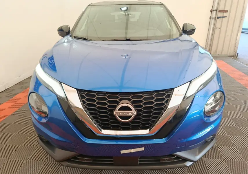 Vue frontale d'un Nissan Juke bleu 2025 avec calandre hexagonale noire et détails chromés brillants.