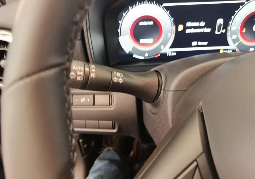 Vue rapprochée du tableau de bord et du volant noir du Nissan Juke 2025, affichage numérique avec compte-tours rouge.