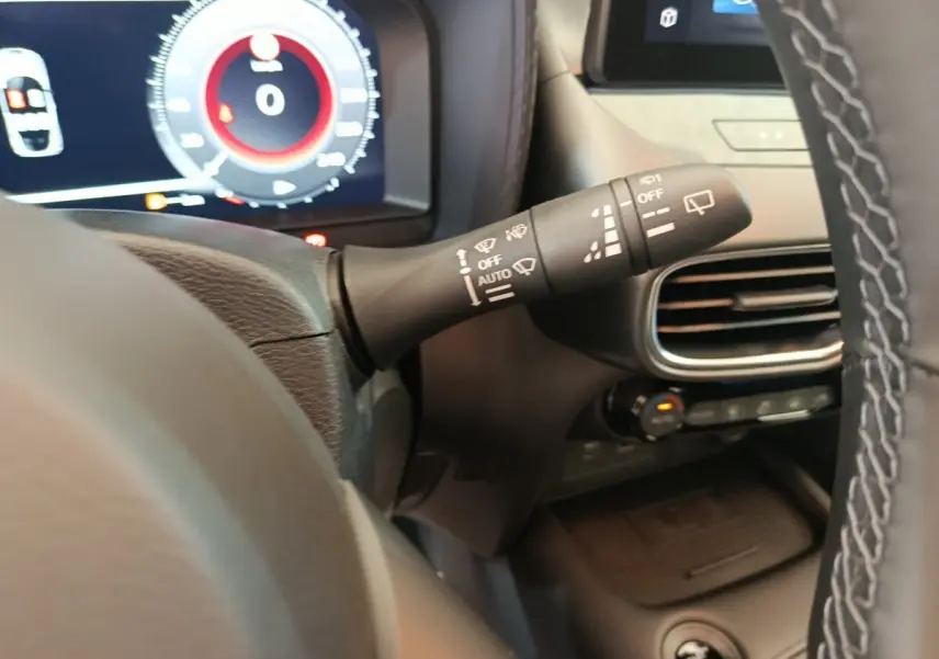 Détail du commodo d’essuie-glace à gauche du volant dans l’habitacle du Nissan Juke bleu 2025.
