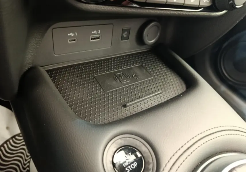 Gros plan sur la console centrale noire du Nissan Juke bleu 2025, avec bouton start/stop et ports USB visibles.