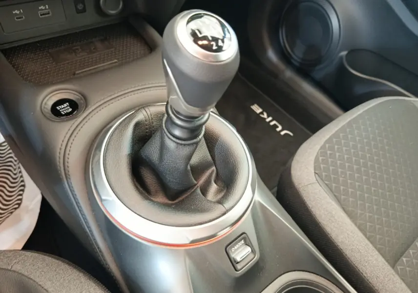Gros plan sur la boîte manuelle et le bouton start/stop dans l’habitacle noir du Nissan Juke 2025.