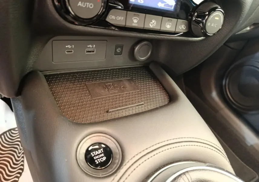Gros plan sur la console centrale noire du Nissan Juke bleu, avec bouton Start/Stop et ports USB visibles.
