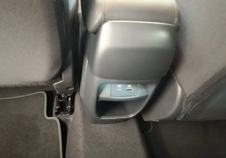 Vue rapprochée de la console arrière noire avec prises USB et éclairage, entre les sièges arrière tissu gris du Nissan Juke bleu.