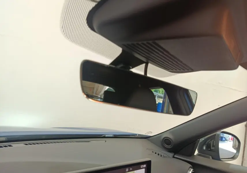 Vue intérieure du tableau de bord du Nissan Juke bleu 2025, avec écran tactile de navigation et rétroviseur central visible.