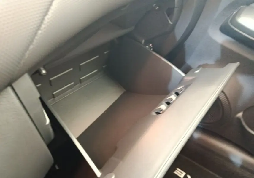 Vue rapprochée de la boîte à gants ouverte côté passager dans l’habitacle noir du Nissan Juke bleu 2025.