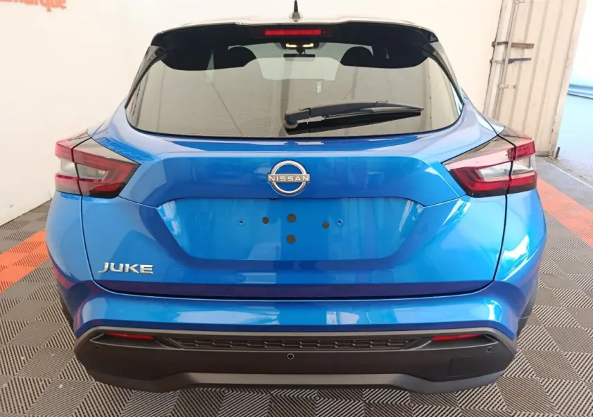 Vue arrière d'un Nissan Juke bleu 2025 avec feux LED et logo Nissan bien visibles sur un sol à damier.