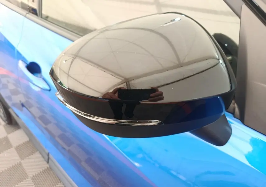 Rétroviseur côté gauche noir brillant avec clignotant intégré sur Nissan Juke bleu vue rapprochée.