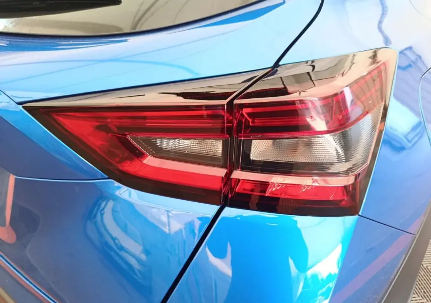 Gros plan sur le feu arrière droit rouge et blanc du Nissan Juke bleu 2025, soulignant la carrosserie brillante.