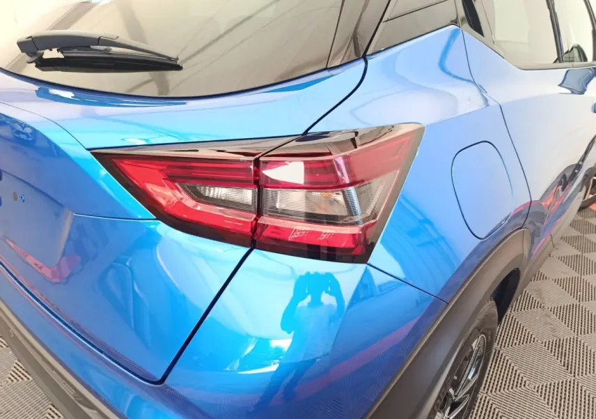 Vue 3/4 arrière droite du Nissan Juke bleu 2025, mettant en valeur le feu arrière et la trappe à carburant.
