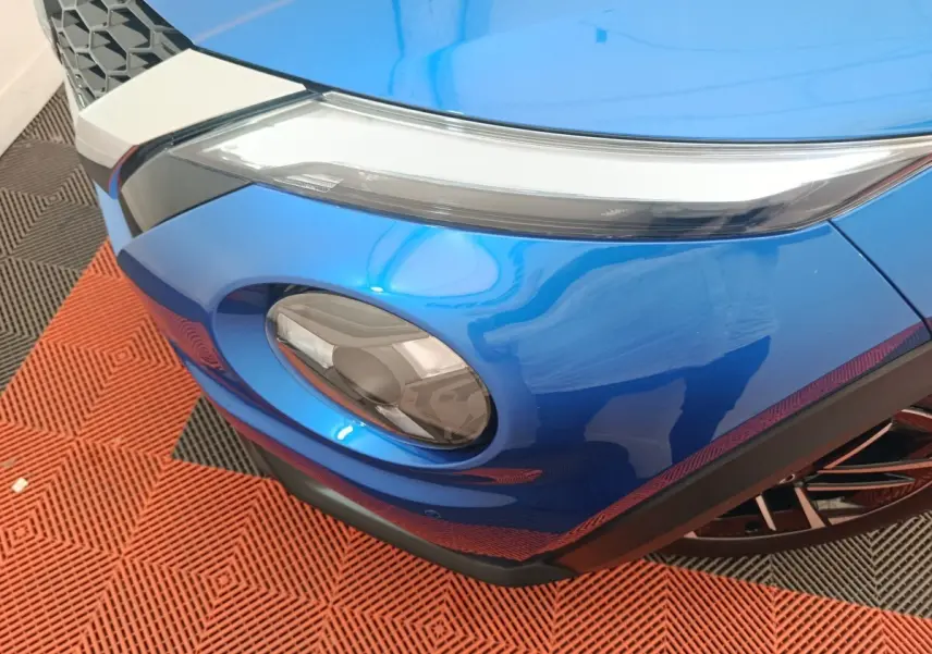 Gros plan sur le phare avant droit bleu du Nissan Juke 2025 avec partie supérieure fine et rondeur inférieure.