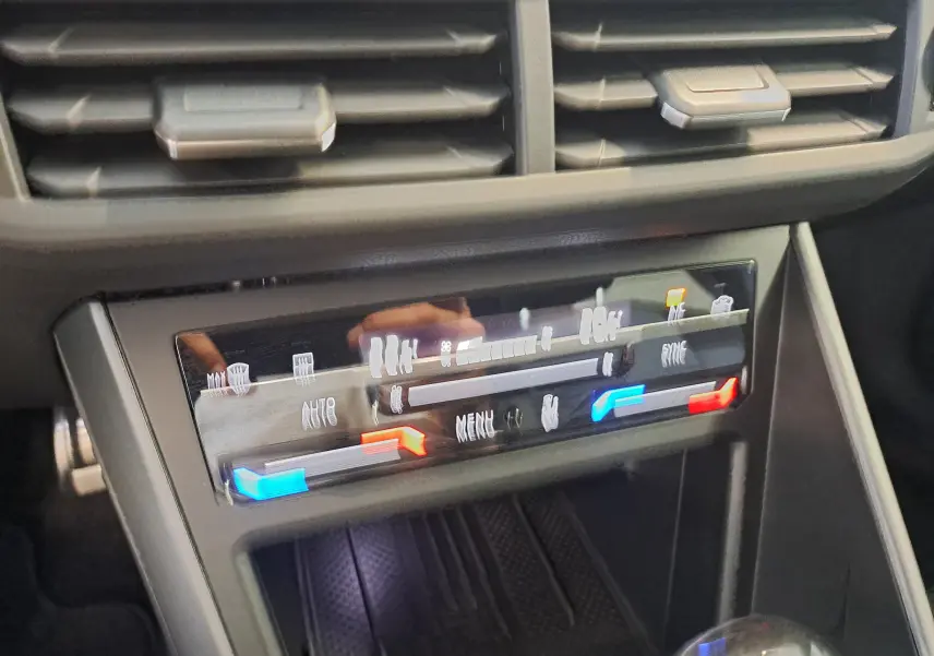 Détail du tableau de bord du Volkswagen Taigo 2025 montrant la commande de climatisation avec éclairage bleu et rouge.