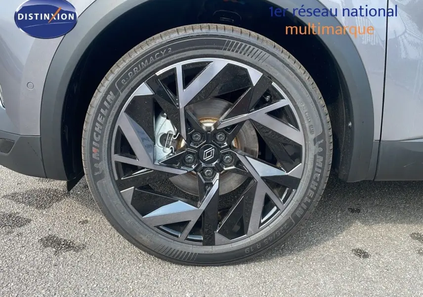 Gros plan sur la roue avant gauche du Renault Captur gris Cassiopée avec jante alliage noire au design géométrique.