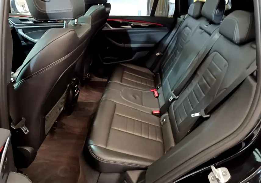 Vue côté droit de la banquette arrière en cuir noir du BMW X3 xDrive20d 2019 avec finitions Luxury et ceintures rouges.
