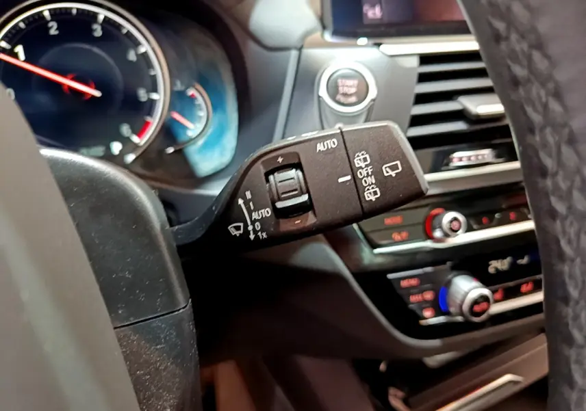 Gros plan sur la commande d’essuie-glace à gauche du volant dans l’habitacle noir du BMW X3 2019.