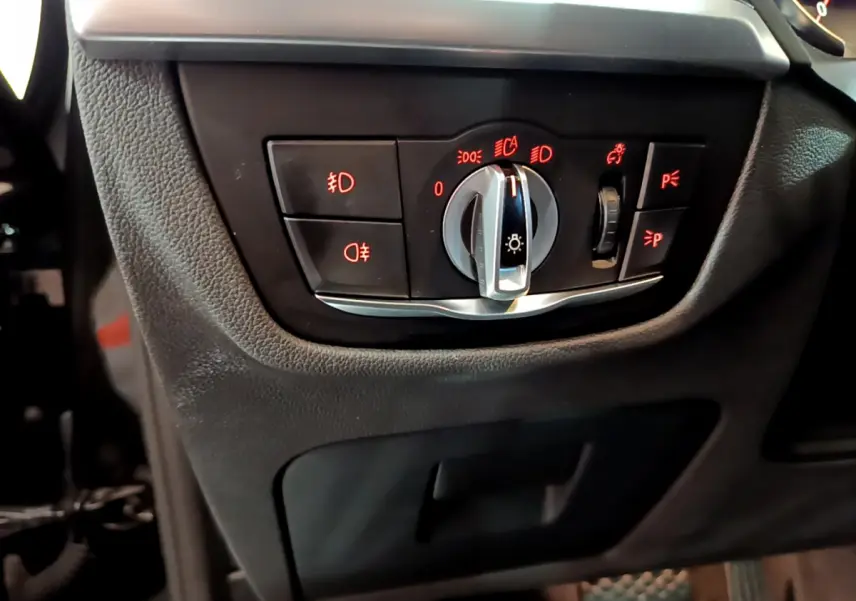 Gros plan sur la commande d'éclairage noire avec voyants rouges dans l'habitacle du BMW X3 noir 2019.