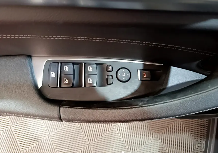 Gros plan sur les commandes de lève-vitres et rétroviseurs côté conducteur du BMW X3 noir 2019 Luxury.