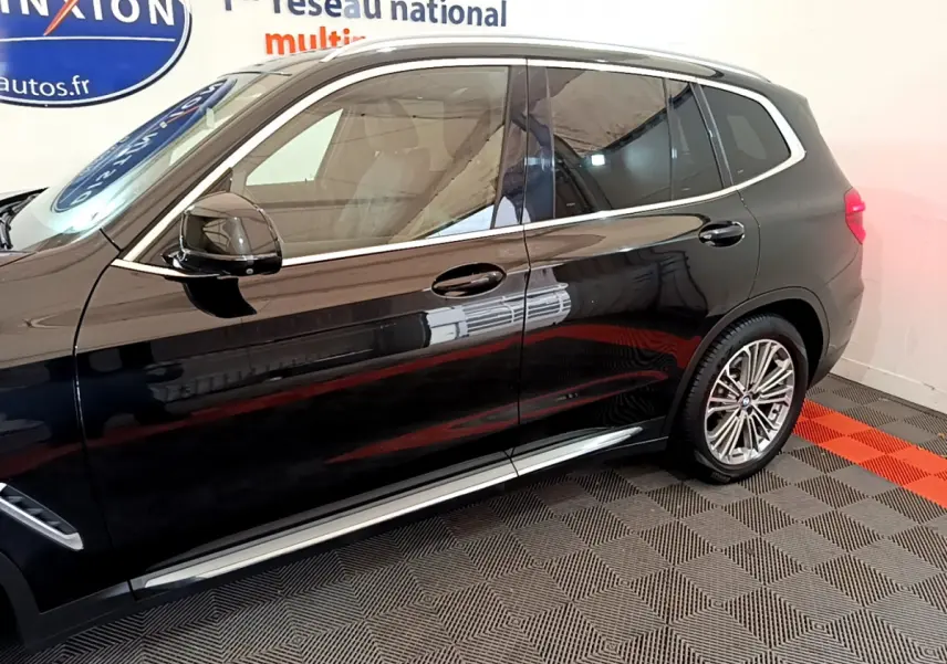 Profil côté gauche d'un BMW X3 noir 2019 avec jantes alliage et vitres teintées dans un showroom.