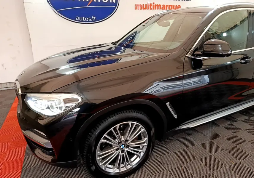 BMW X3 xDrive20d noir vu de 3/4 avant droit avec jantes alliage et phares LED allumés