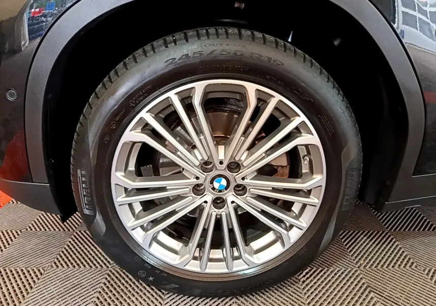 Gros plan sur la roue avant droite du BMW X3 noir, mettant en valeur la jante alliage multi-branches et le pneu Pirelli.