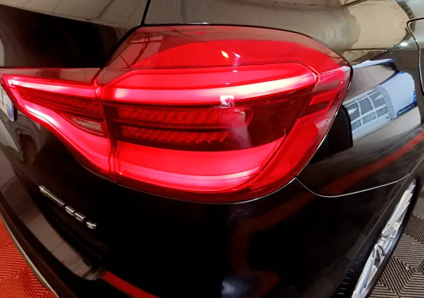Gros plan sur le feu arrière droit rouge d’un BMW X3 noir 2019, soulignant la finition xDrive20d Luxury.
