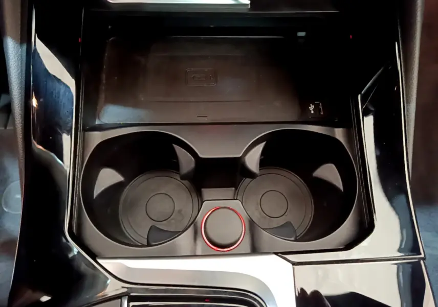 Gros plan sur la console centrale noire du BMW X3 xDrive20d 2019, avec porte-gobelets et molette rouge.