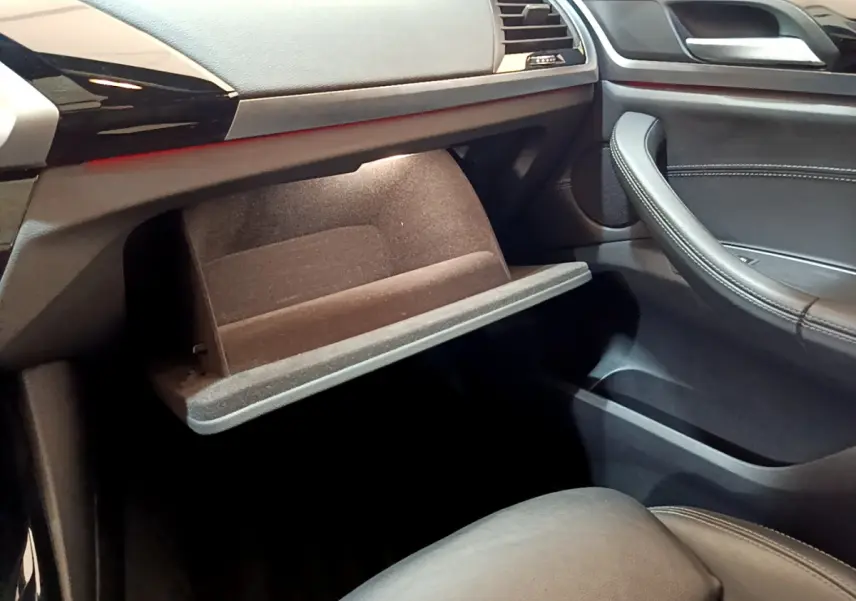 Intérieur côté passager d'une BMW X3 noire 2019, boîte à gants ouverte avec garniture noire et détails cuir.