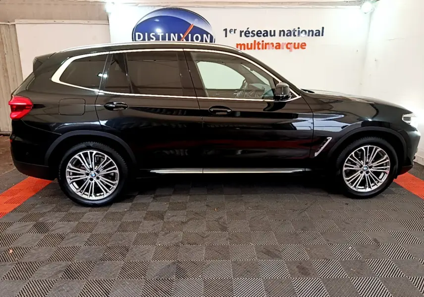 Profil côté droit d'un BMW X3 noir 2019 avec jantes alliage et vitres teintées dans un showroom intérieur.
