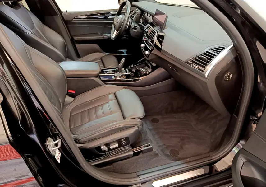 Intérieur noir du BMW X3 xDrive20d 2019 vu côté passager avant, avec sièges cuir et tableau de bord moderne.